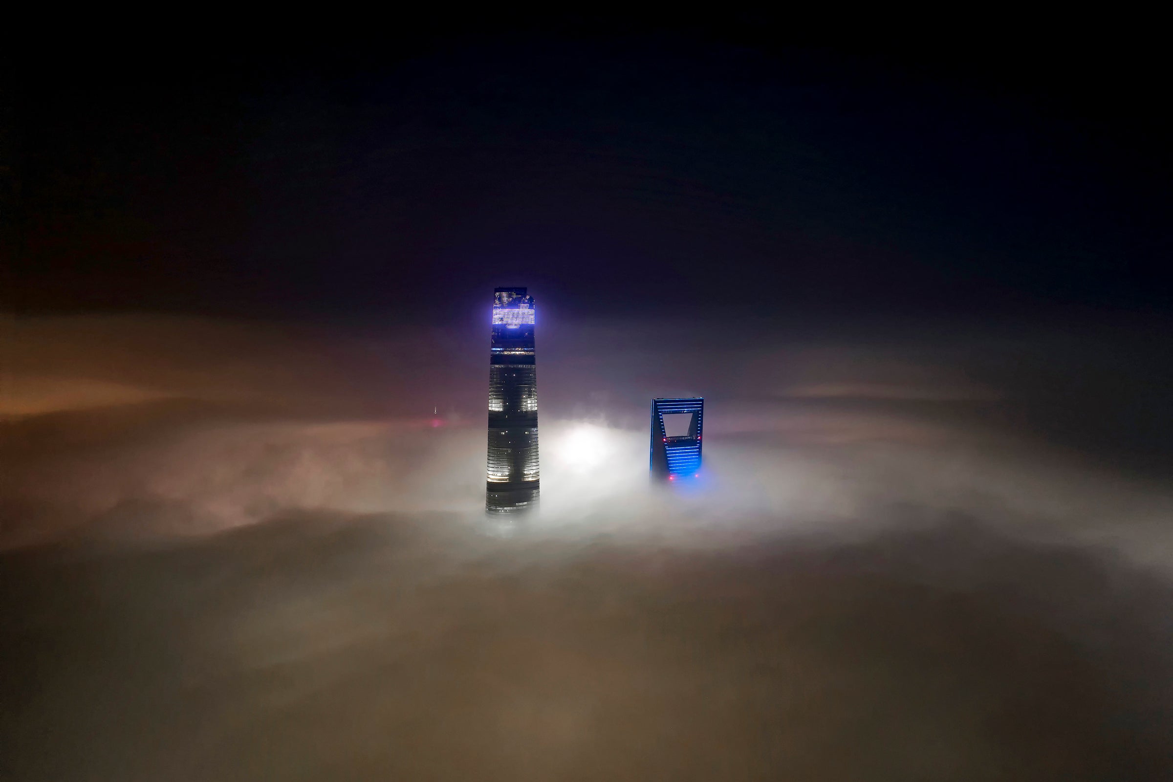 Shanghai tower and Shanghai world financial poke out of the fog at night